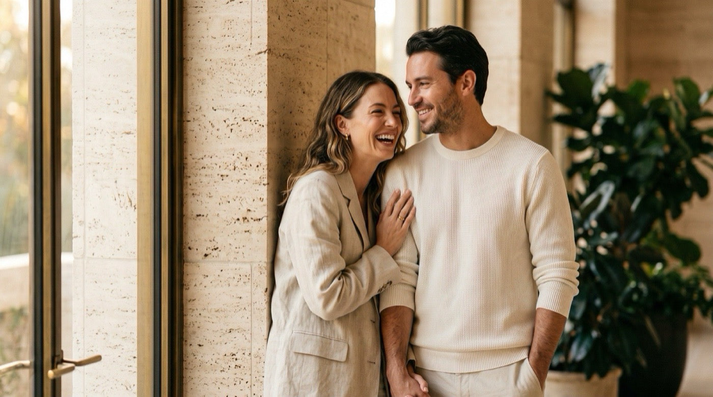Two people standing close together in warm afternoon light, one leaning in mid-conversation, relaxed and confident